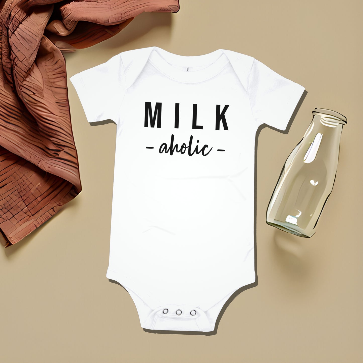 White baby bodysuit with "MILK -aholic -" text on a beige background with draped fabric and a milk bottle. A funny humorous and relatable baby clothes design about feeding from Born Brash.