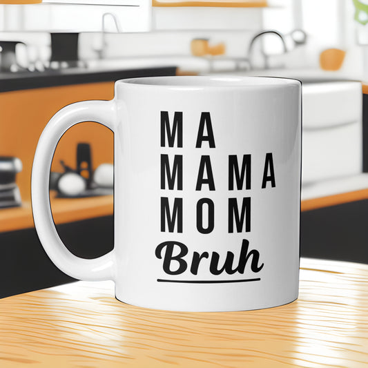 White ceramic mug with "MA MAMA MOM Bruh" text on a kitchen counter. A funny humorous parenting mug, making it a great baby shower gift for expecting or new moms from Born Brash.