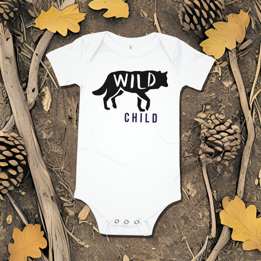 White baby bodysuit with a wolf silhouette graphic and "WILD CHILD" text on a background of bark, pinecones, and oak leaves. A bold unique baby clothes design perfect as a baby shower gift from Born Brash for little wild ones.
