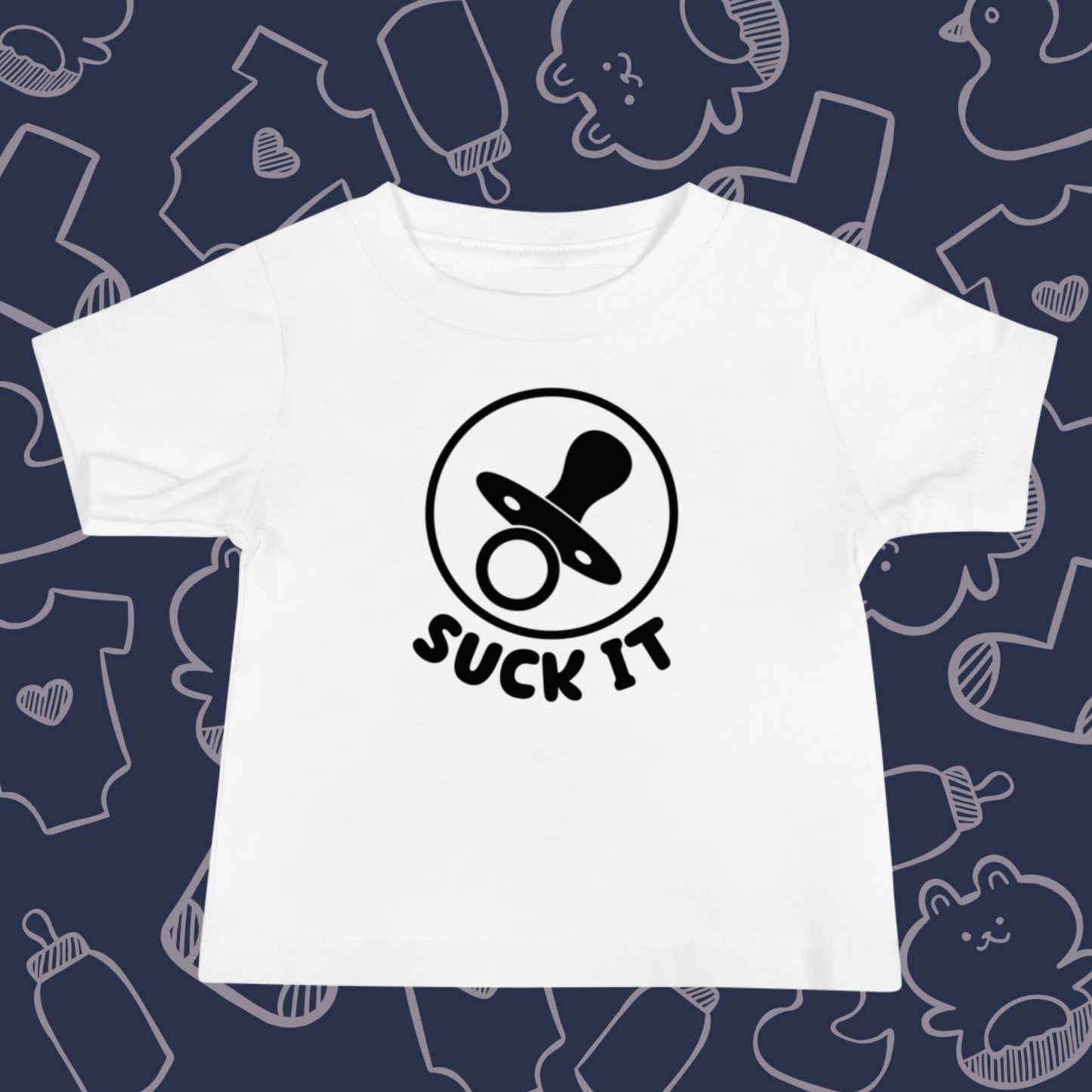 Funny, white baby t-shirt featuring an image of a pacifier and the playful text "SUCK IT" against a whimsical, blue backdrop of ducks, socks, stuffed animals, baby bodysuits, and bottles