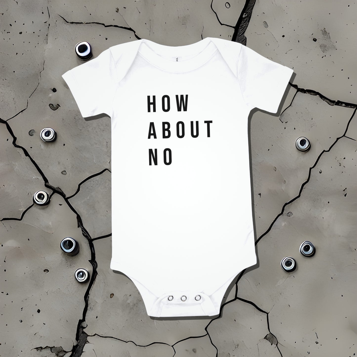 White baby bodysuit with "HOW ABOUT NO" text displayed on a cracked surface. A bold statement baby clothes design conveying sarcastic attitude from Born Brash.