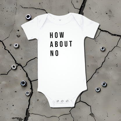 White baby bodysuit with "HOW ABOUT NO" text displayed on a cracked surface. A bold statement baby clothes design conveying sarcastic attitude from Born Brash.