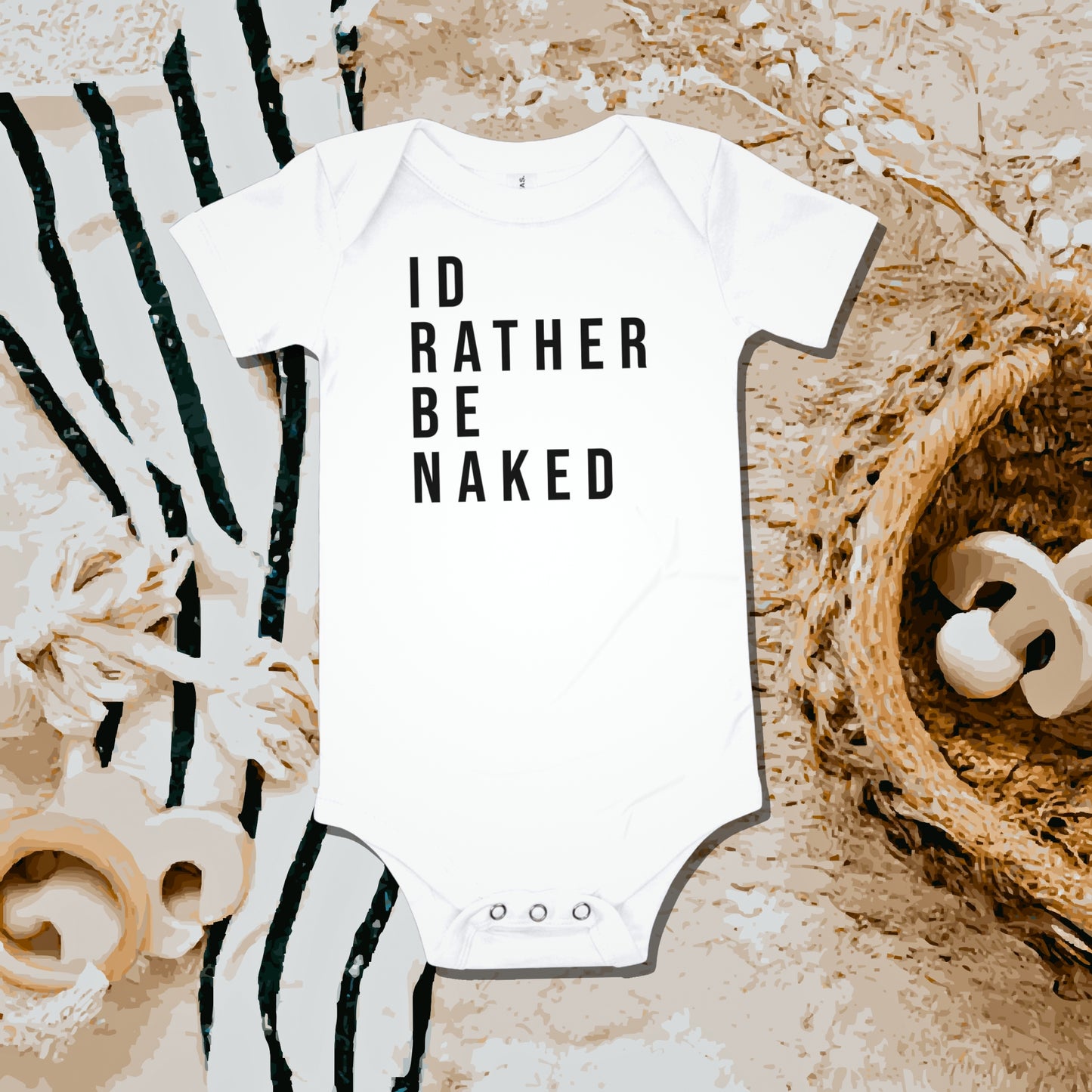 White baby bodysuit with "ID RATHER BE NAKED" text on a fuzzy blanket with striped fabric and basket. A funny humorous and relatable baby clothes design about not wanting to wear clothes from Born Brash.