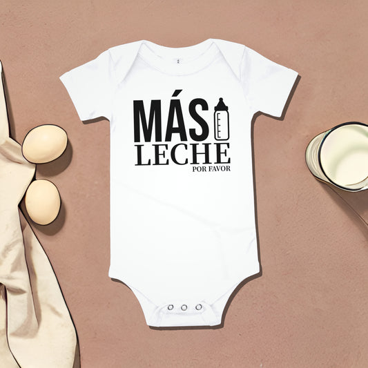 White baby bodysuit with "MÁS LECHE POR FAVOR" text and baby bottle graphic, on a dark brown background with egg and cup illustrations. A funny humorous baby clothes design about wanting more milk, perfect as a relatable baby shower gift from Born Brash.