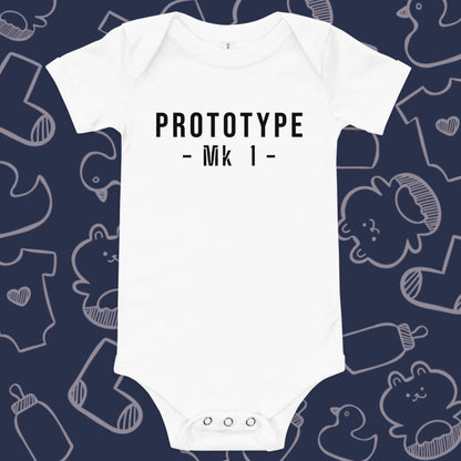 Funny, white baby onesie featuring the playful text "PROTOTYPE MK 1" against a whimsical, blue backdrop of ducks, socks, stuffed animals, baby bodysuits, and bottles