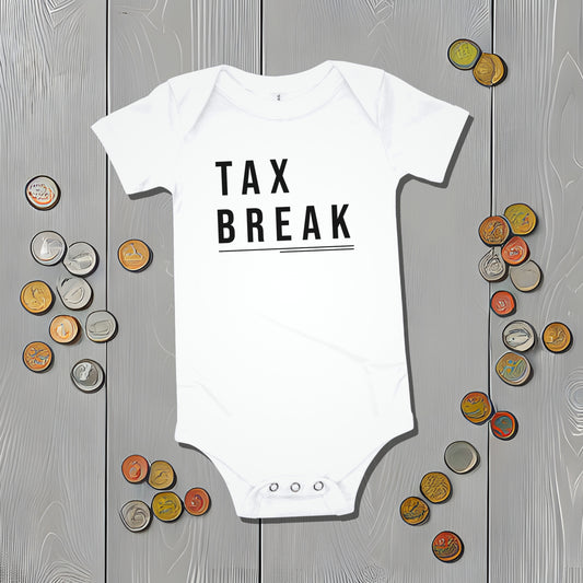 White baby bodysuit with "TAX BREAK" text on a gray wooden background surrounded by coin illustrations. A funny humorous and relatable baby clothes design for new parents from Born Brash.