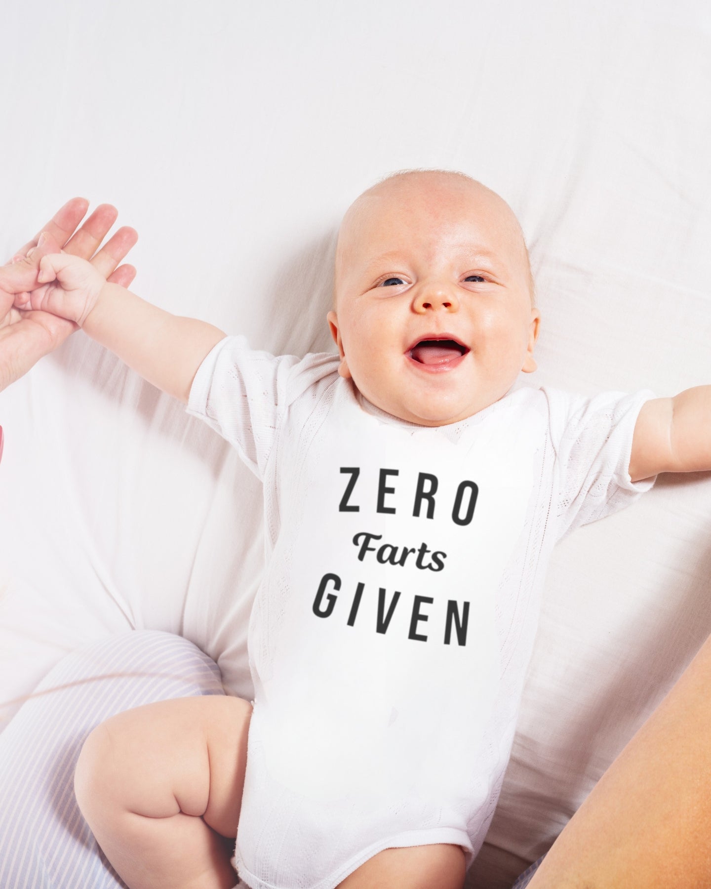 Photo of a smiling baby wearing a white bodysuit with the funny saying "ZERO FARTS GIVIN" in black font.