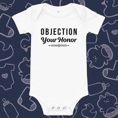 Funny, white baby bodysuit featuring the playful text "OBJECTION Your Honor" underlined against a whimsical, blue backdrop of baby toys, bodysuits, and bottles.