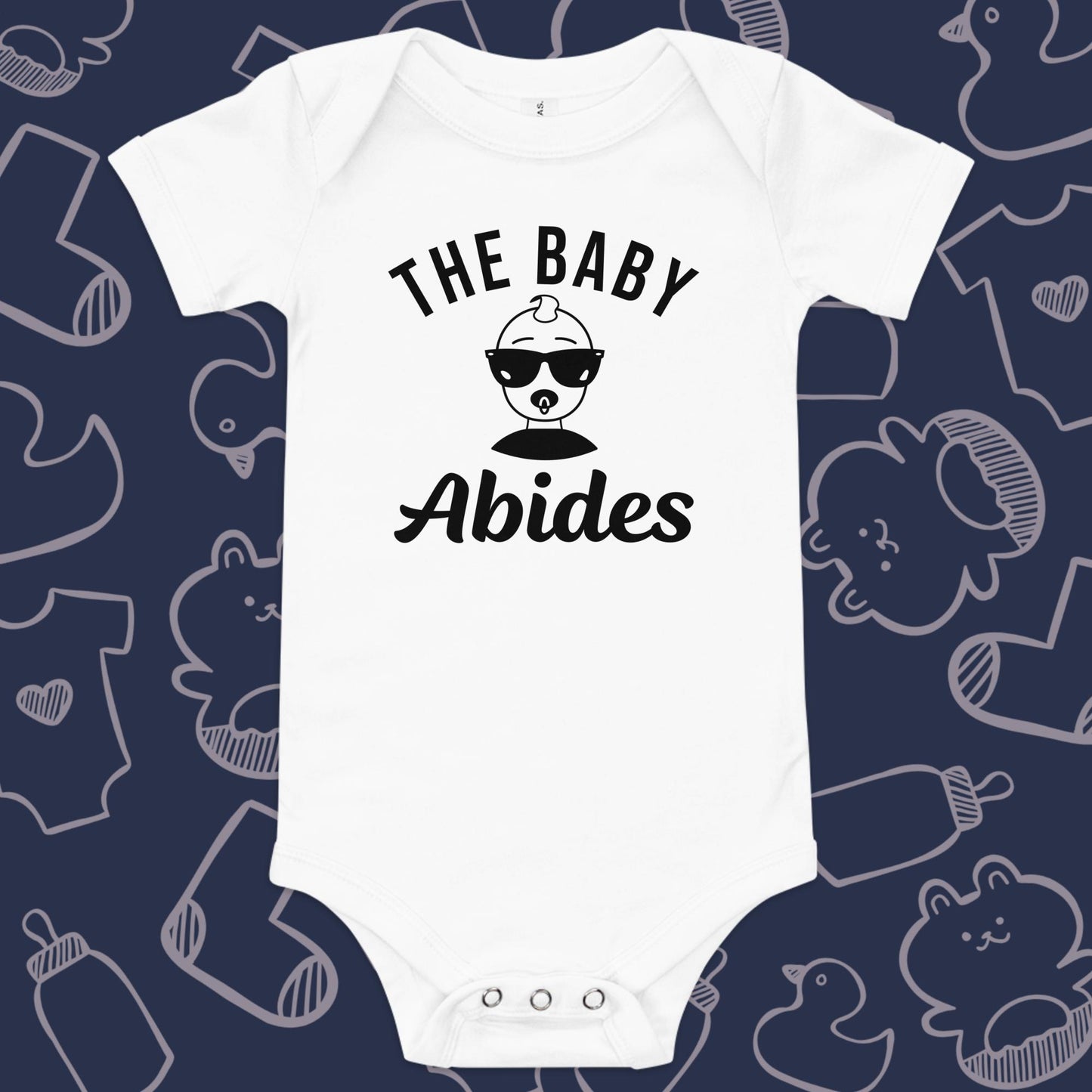 Funny, white baby bodysuit featuring the playful text "The Baby Abides" and an illustration of a cool baby wearing sunglasses against a whimsical, blue backdrop of baby toys, bodysuits, and bottles.